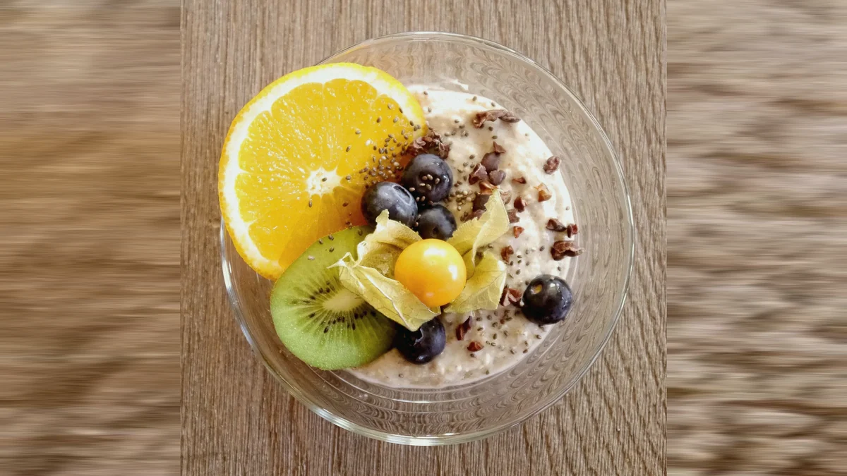 Cuenco de avena remojada con naranja, kiwi, arándanos y semillas, visto desde arriba