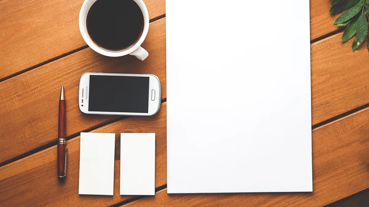 Cuaderno, café y teléfono móvil sobre una mesa de madera