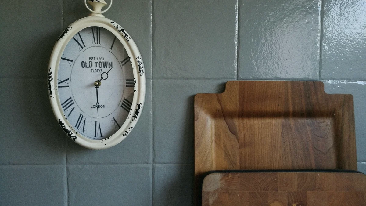 Reloj de pared de estilo antiguo en una cocina, junto a dos tablas de cortar de madera