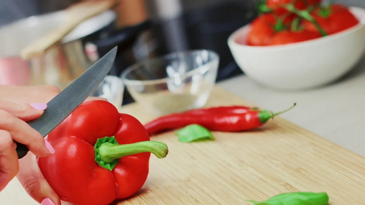 Pimiento rojo troceado sobre una tabla de madera, junto a un cuchillo