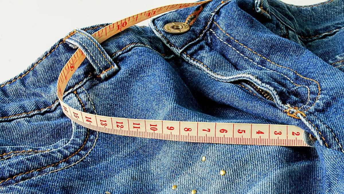 Cinta métrica de costura enrollada sobre un pantalón vaquero