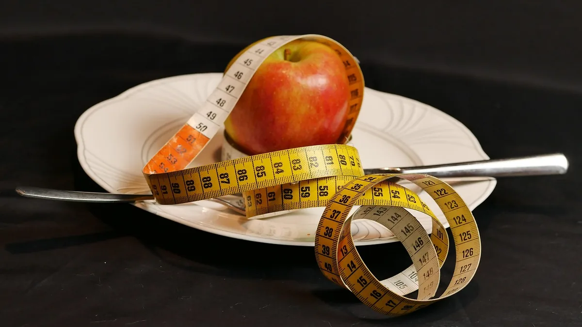 Manzana con una cinta métrica enrollada, sobre un plato
