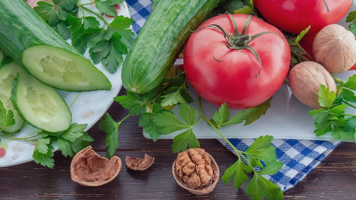 Pepinos, tomates y perejil sobre una tabla de cocina
