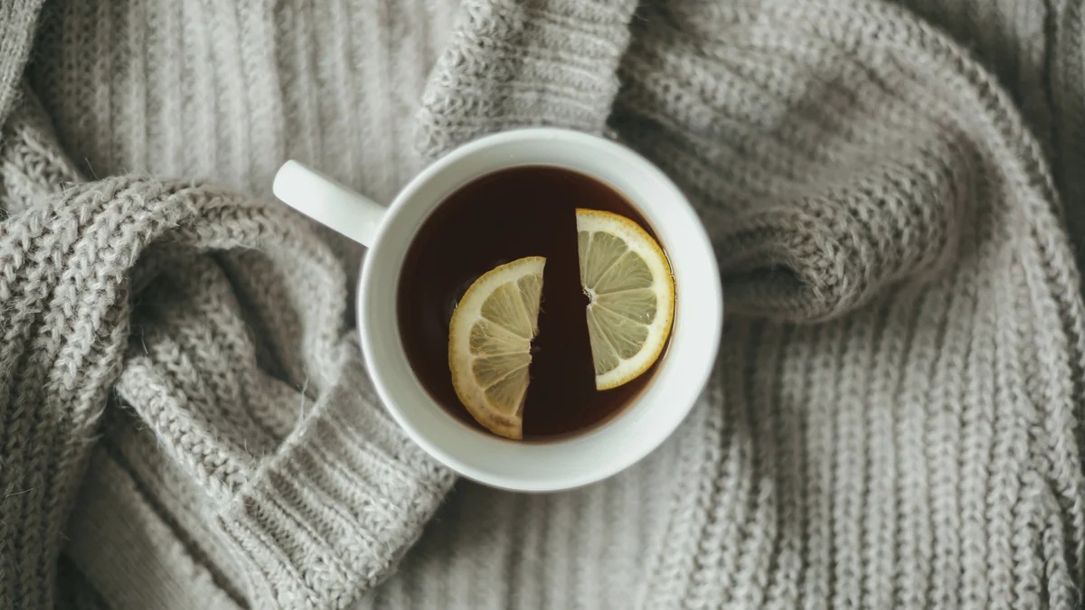 Taza de té con dos rodajas de limón sobre un jersey de lana gris