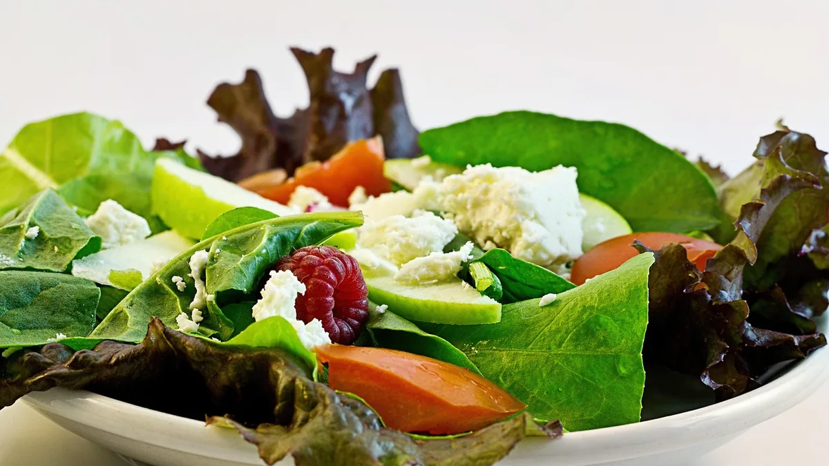 Plato de ensalada con hoja verde, tomate y queso