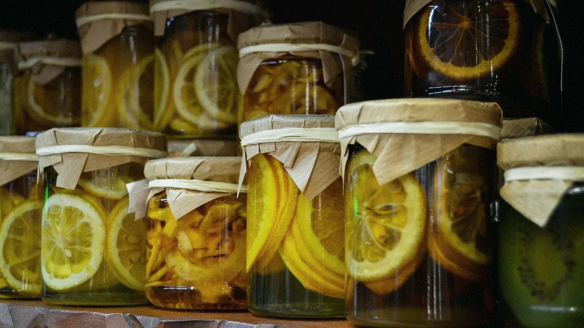 Tarros de conserva de fruta en almíbar con la boca cubierta de tela atada, en fila