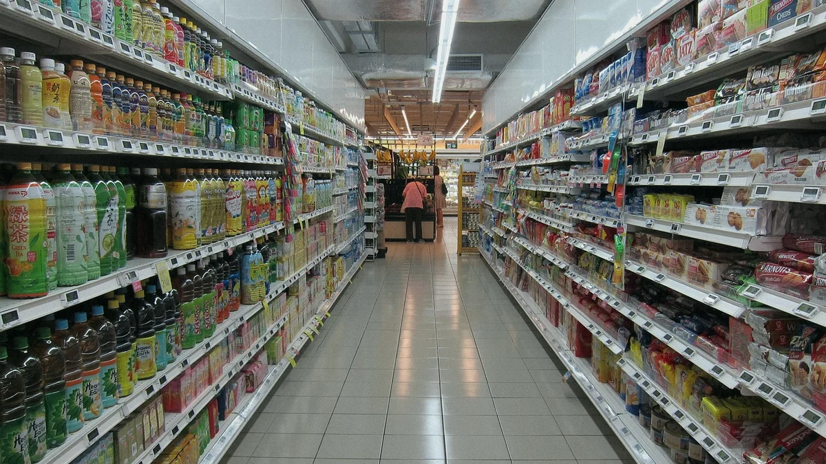 Pasillo de supermercado vacío, con los lineales llenos a ambos lados y el suelo brillante