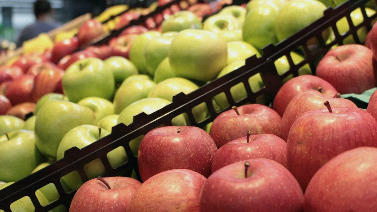 Manzanas rojas y verdes colocadas en cajas inclinadas del lineal de fruta de un supermercado