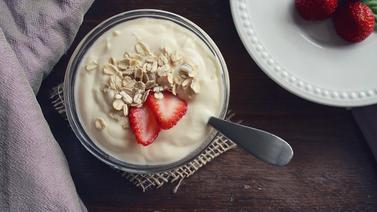 Cuenco de yogur con cereales y fresa sobre una mesa oscura