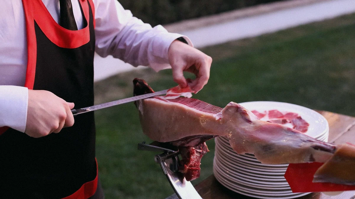 Un cortador de jamón corta lonchas finas de un jamón ibérico