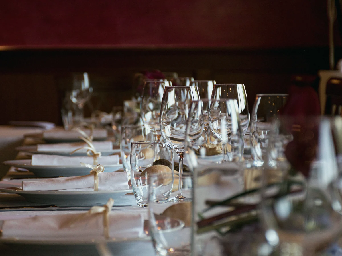 Mesa larga de restaurante preparada con copas de vino vacías y servilletas blancas
